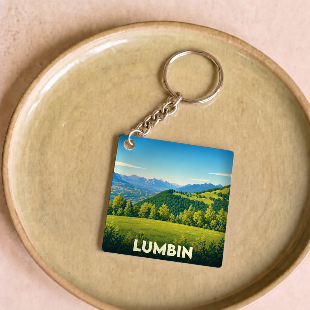 Porte-clés souvenir de la ville de Lumbin avec une illustration stylisée de paysages montagneux.
