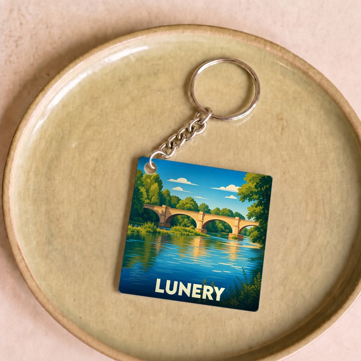 Porte-clés souvenir de la ville de Lunery avec une illustration stylisée d'un pont enjambant une rivière.