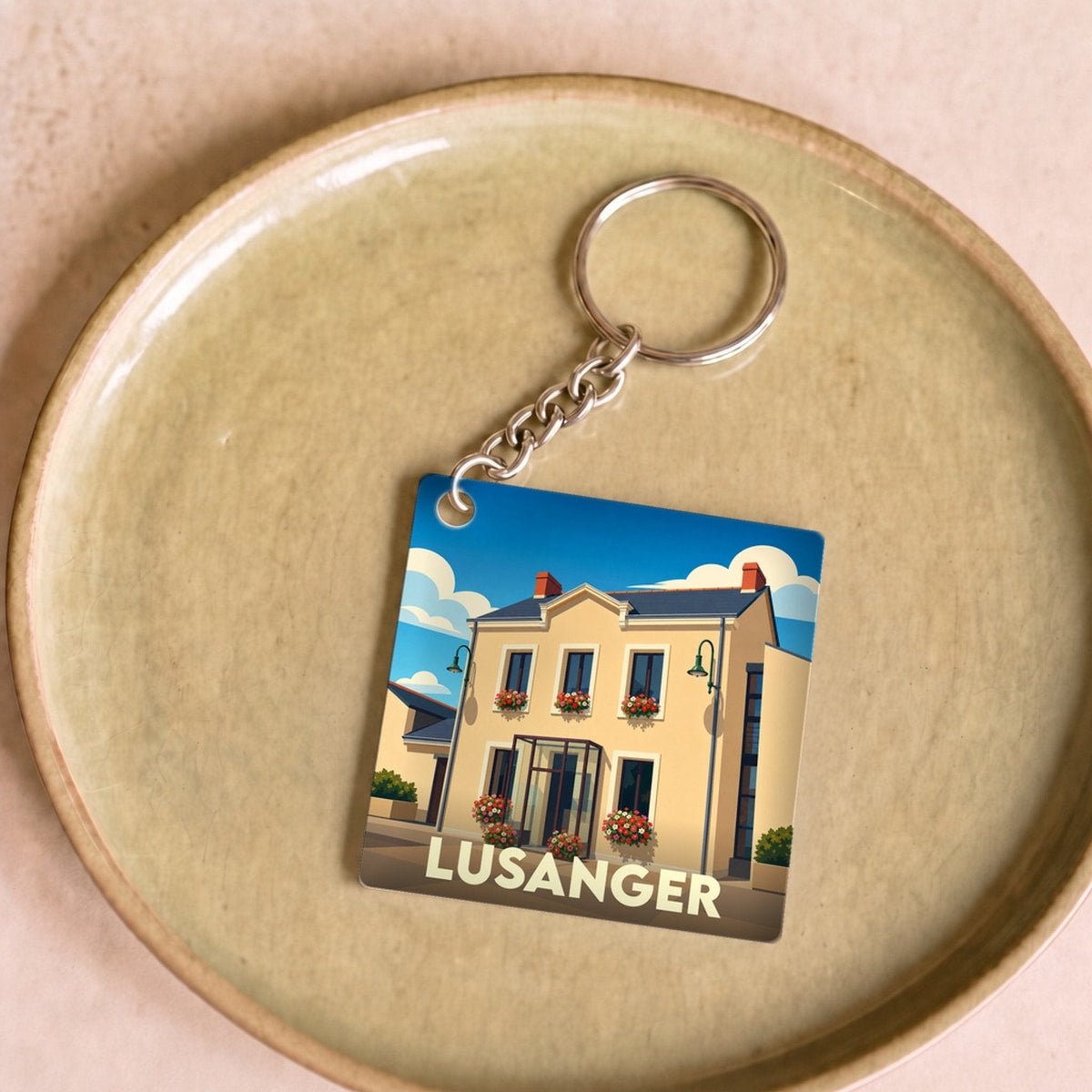 Porte-clés souvenir de la ville de Lusanger avec une illustration stylisée d'un bâtiment fleuri.
