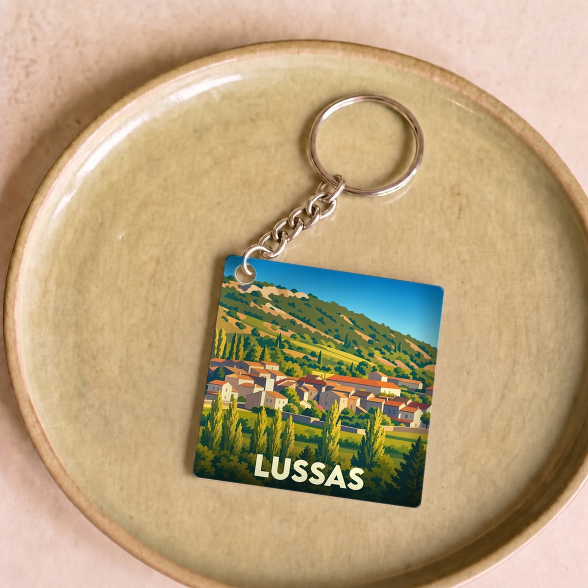 Porte-clés souvenir de la ville de Lussas avec une illustration stylisée de son paysage provençal.