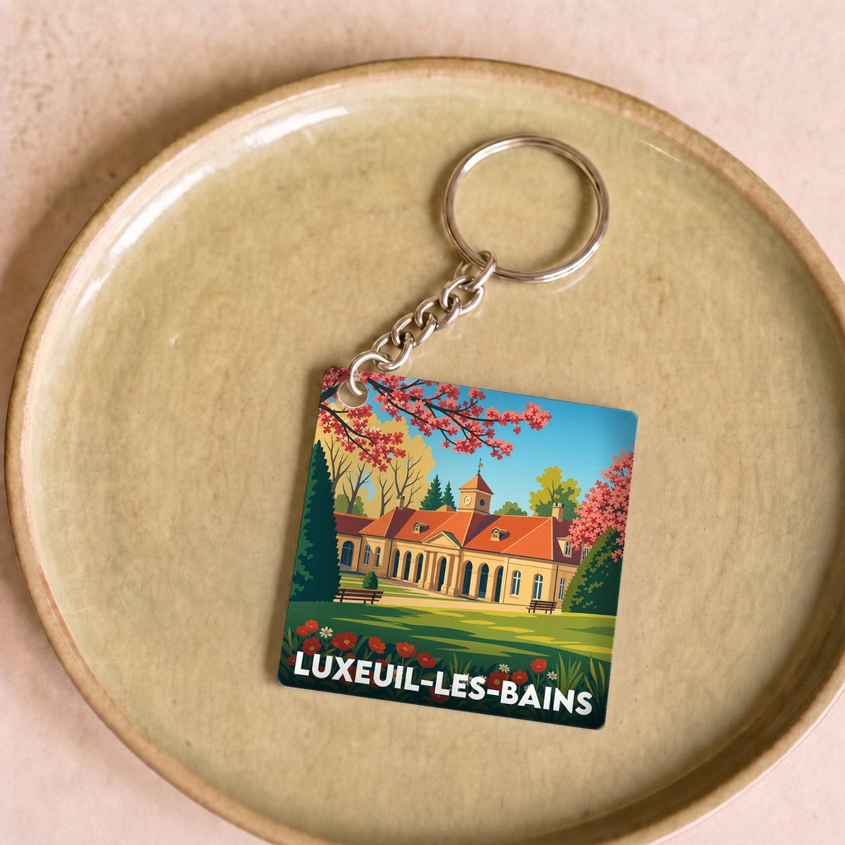 Porte-clés souvenir de la ville de Luxeuil-les-Bains avec une illustration stylisée.