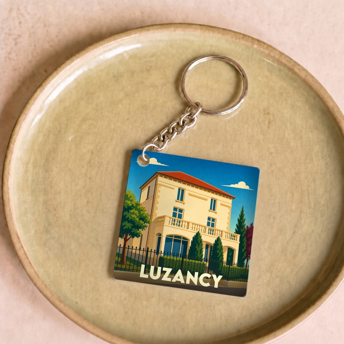 Porte-clés souvenir de la ville de Luzancy avec une illustration stylisée d'une villa.