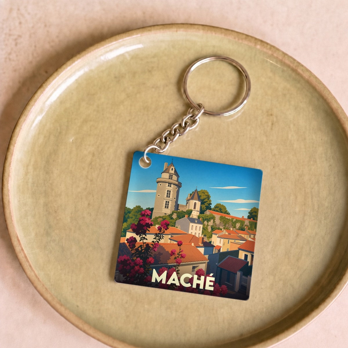 Porte-clés souvenir de la ville de Maché avec une illustration stylisée.