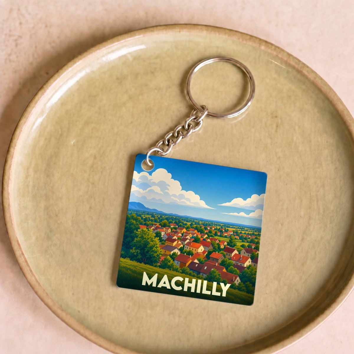 Porte-clés souvenir de la ville de Machilly avec une illustration stylisée de son paysage urbain et champêtre.