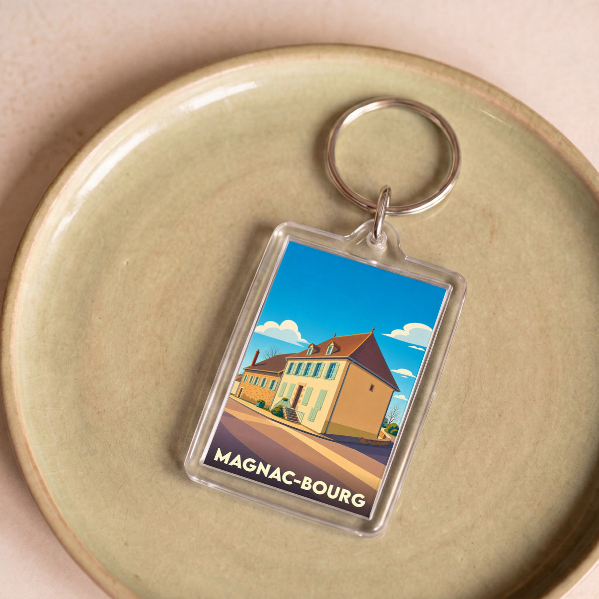 Porte-clés souvenir de la ville de Magnac-Bourg avec une illustration stylisée.