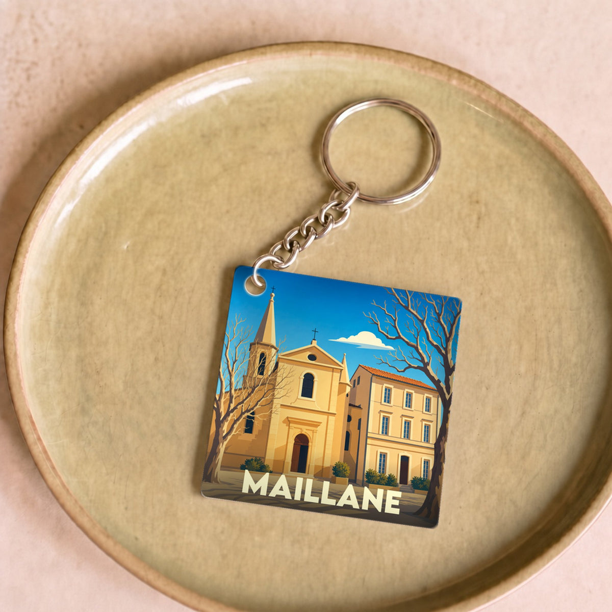 Porte-clés souvenir de la ville de Maillane avec une illustration stylisée.