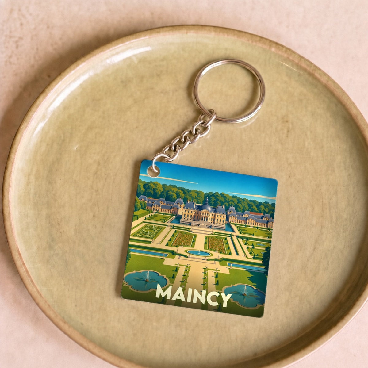 Porte-clés souvenir de la ville de Maincy avec une illustration stylisée du château de Vaux-le-Vicomte.