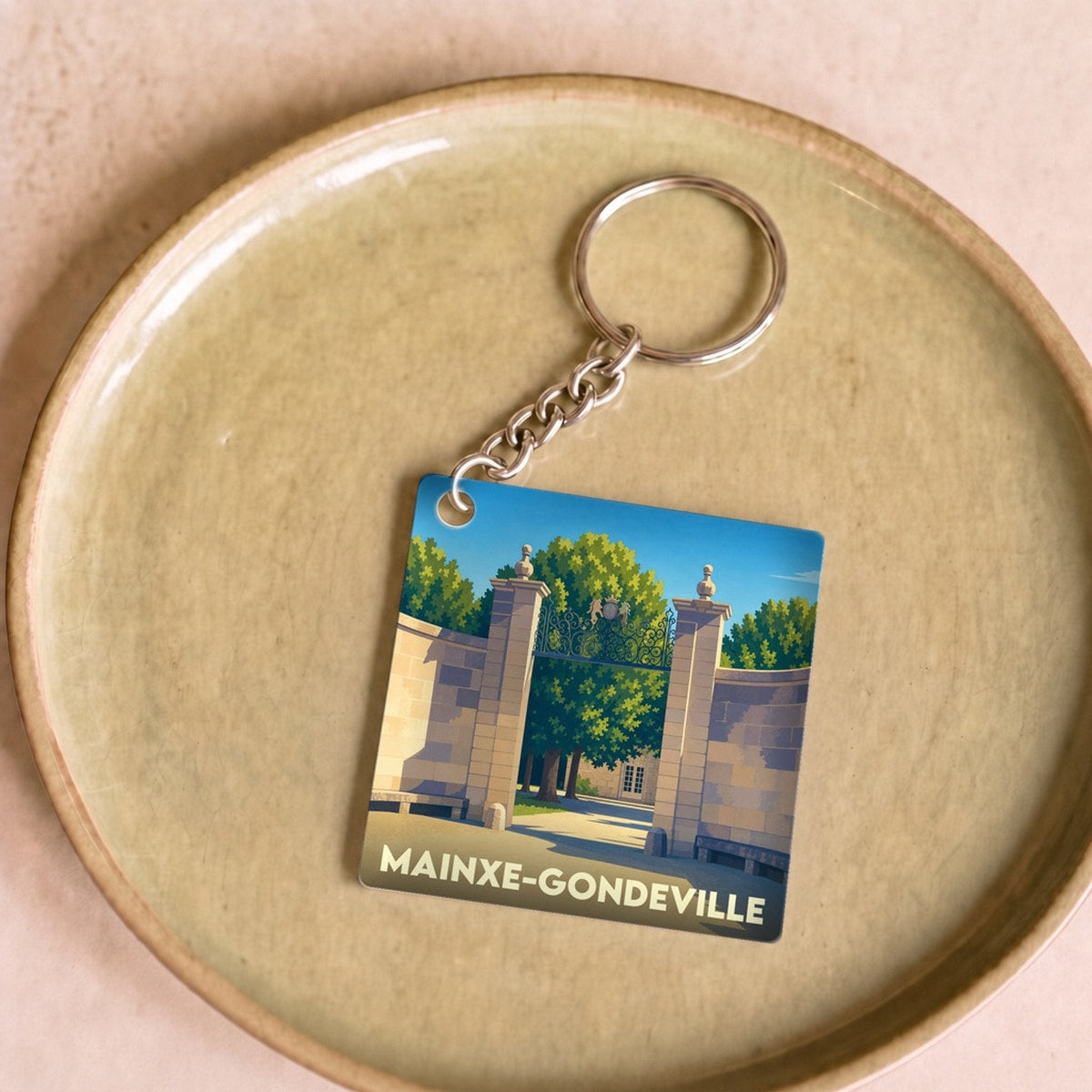Porte-clés souvenir de la ville de Mainxe-Gondeville avec une illustration stylisée d'un portail monumental.