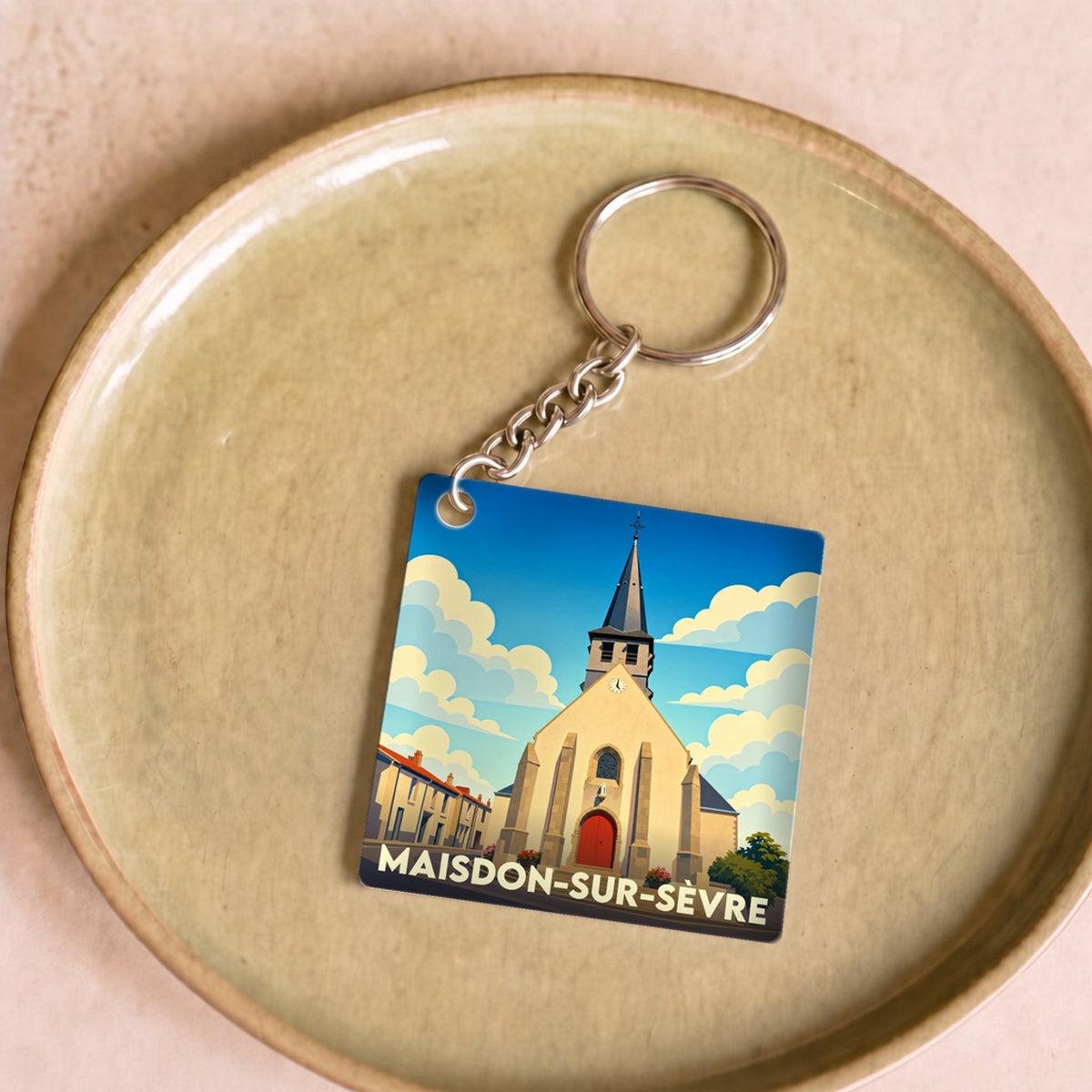 Porte-clés souvenir de la ville de Maisdon-sur-Sèvre avec une illustration stylisée de son église.