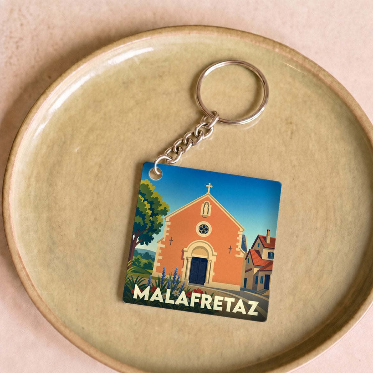 Porte-clés souvenir de la ville de Malafretaz avec une illustration stylisée de son église.