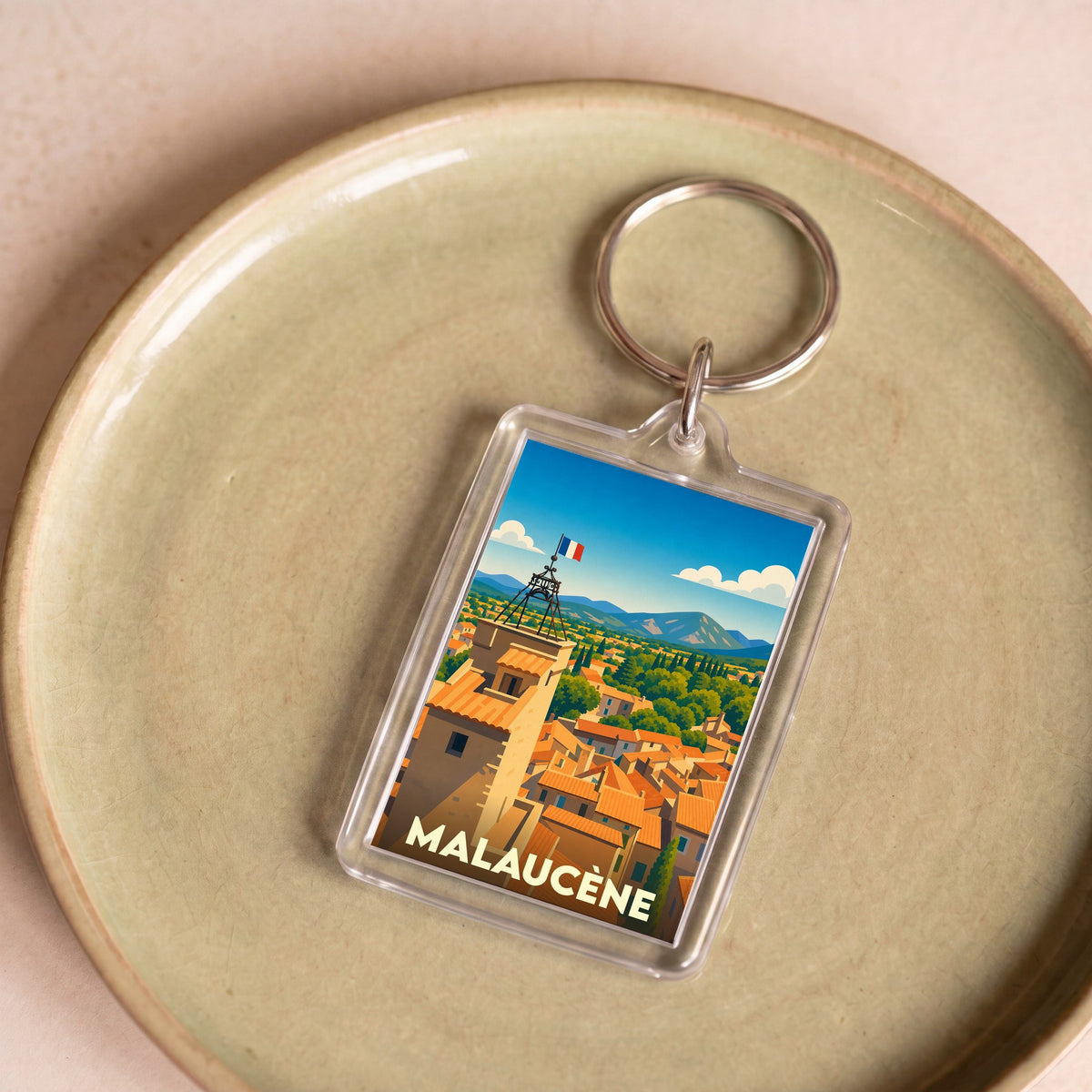 Porte-clés souvenir de la ville de Malaucène avec une illustration stylisée d'un clocher provençal.