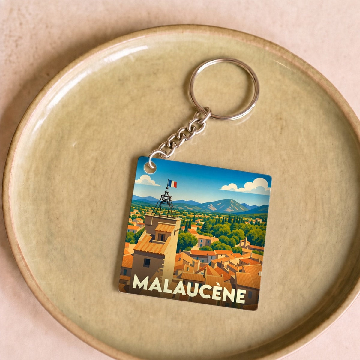 Porte-clés souvenir de la ville de Malaucène avec une illustration stylisée d'un clocher provençal.