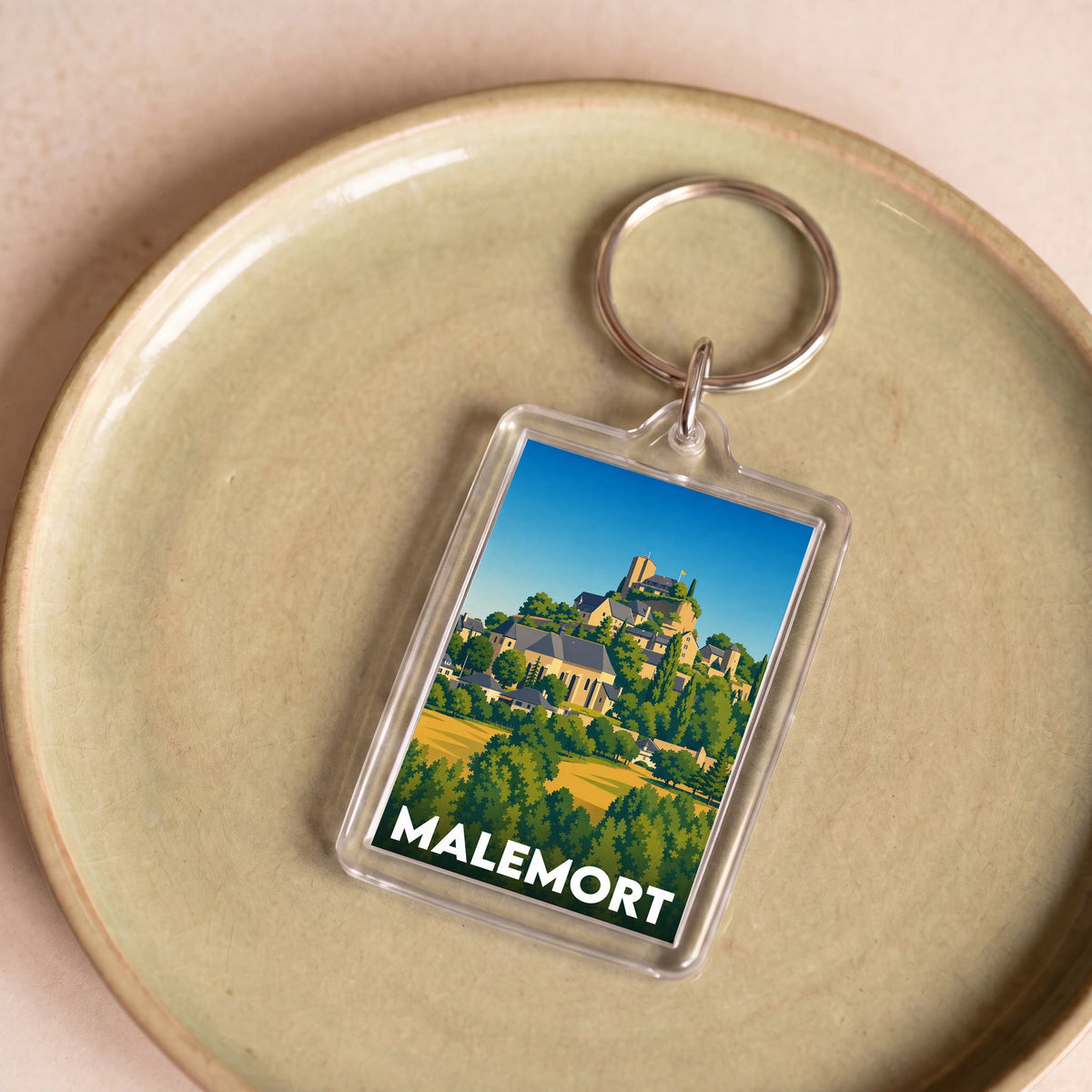Porte-clés souvenir de la ville de Malemort avec une illustration stylisée d'un village perché.