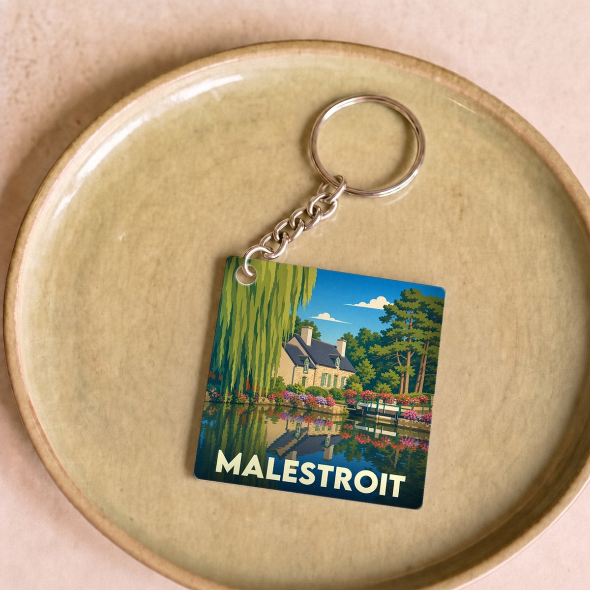 Porte-clés souvenir de la ville de Malestroit avec une illustration stylisée d'un paysage au bord de l'eau.