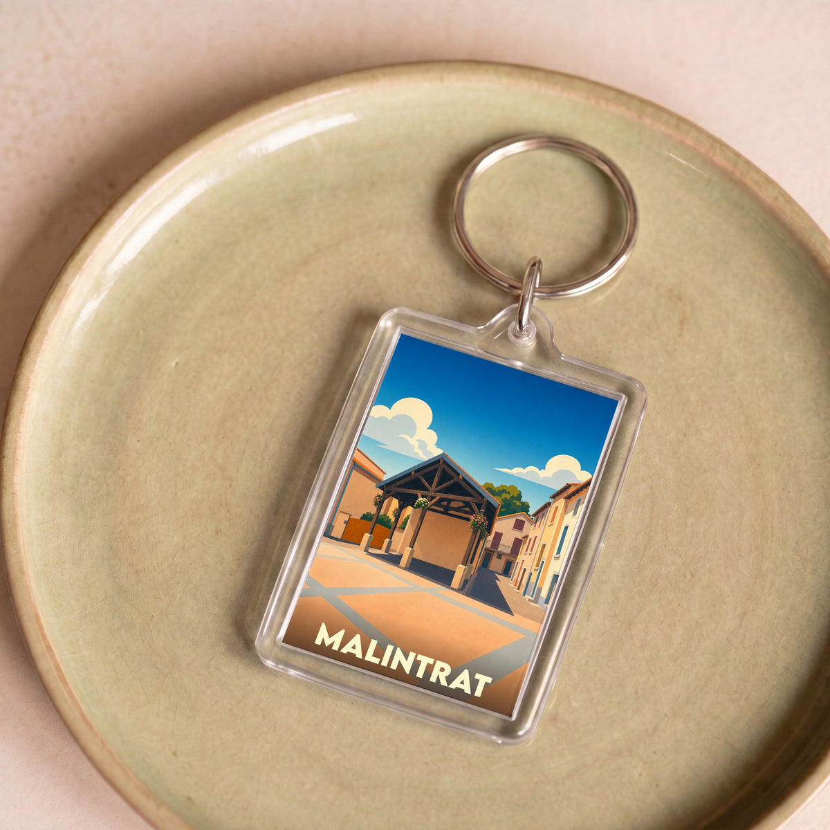 Porte-clés souvenir de la ville de Malintrat avec une illustration stylisée de sa halle couverte.