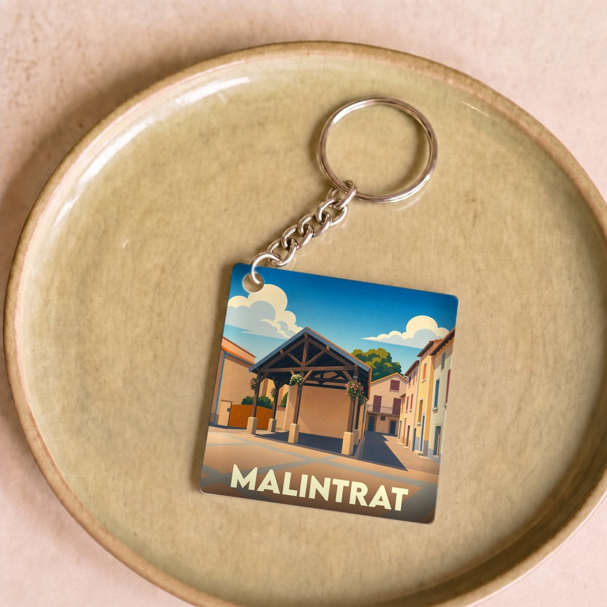 Porte-clés souvenir de la ville de Malintrat avec une illustration stylisée de sa halle couverte.