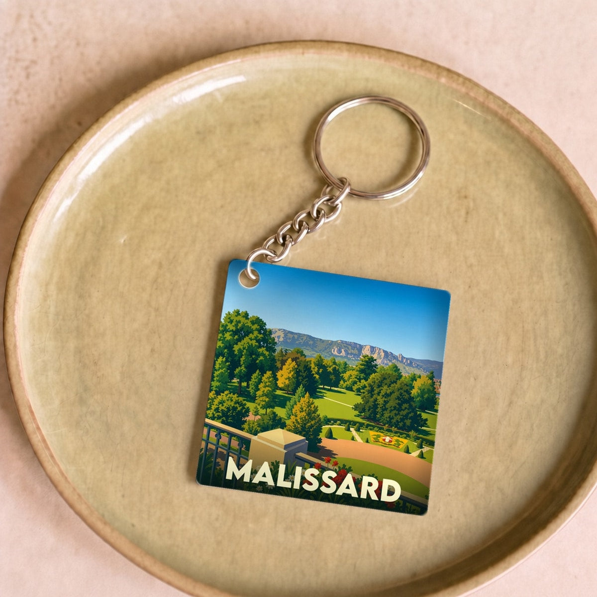 Porte-clés souvenir de la ville de Malissard avec une illustration stylisée de son paysage.