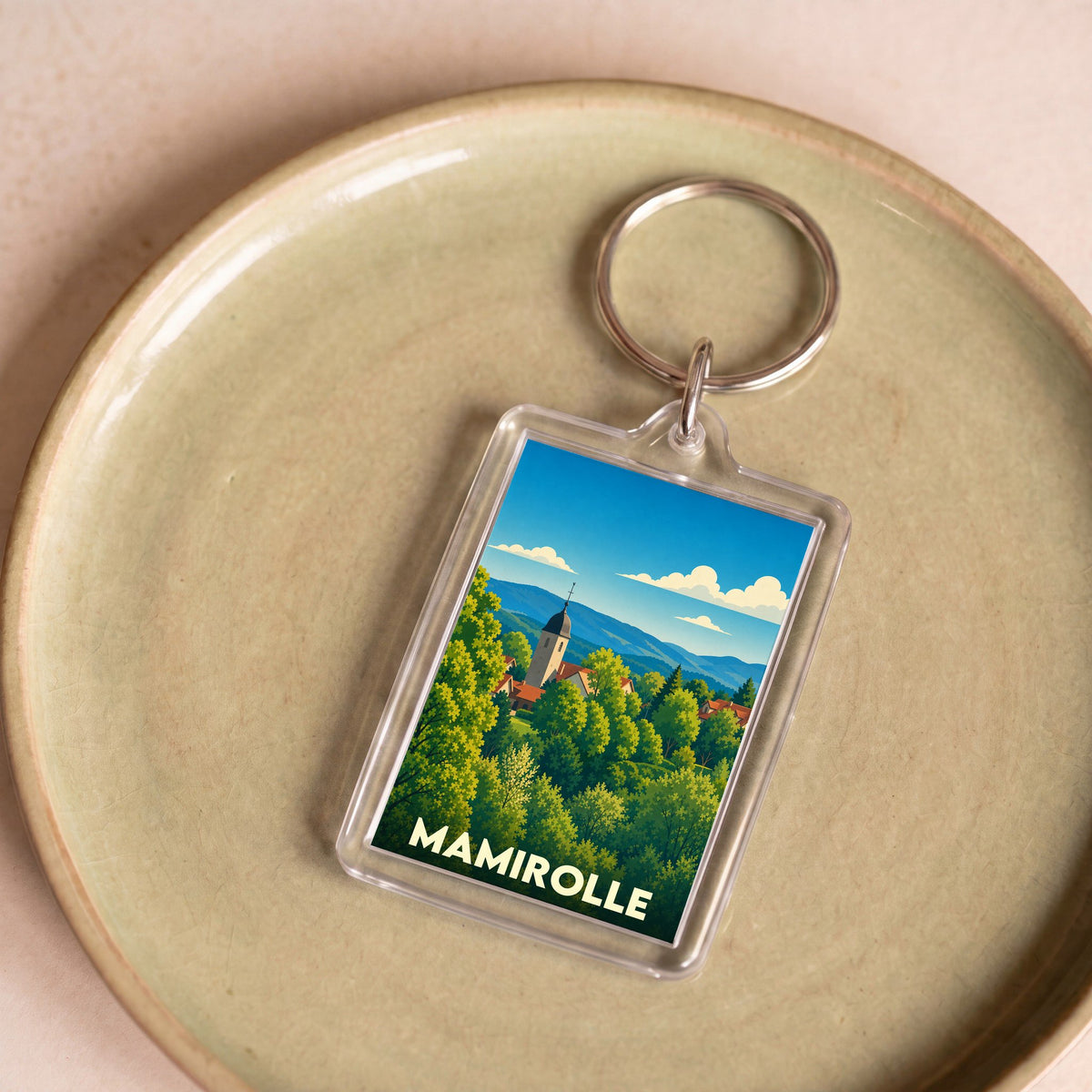 Porte-clés souvenir de la ville de Mamirolle avec une illustration paysagère stylisée.