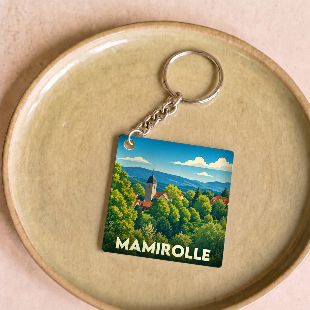 Porte-clés souvenir de la ville de Mamirolle avec une illustration paysagère stylisée.