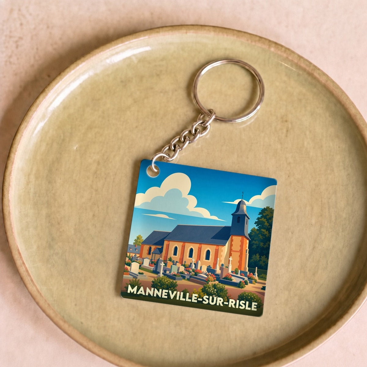 Porte-clés souvenir de la ville de Manneville-sur-Risle avec une illustration stylisée de son église.