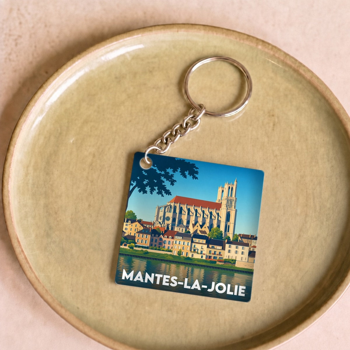 Porte-clés souvenir de la ville de Mantes-la-Jolie avec une illustration stylisée.