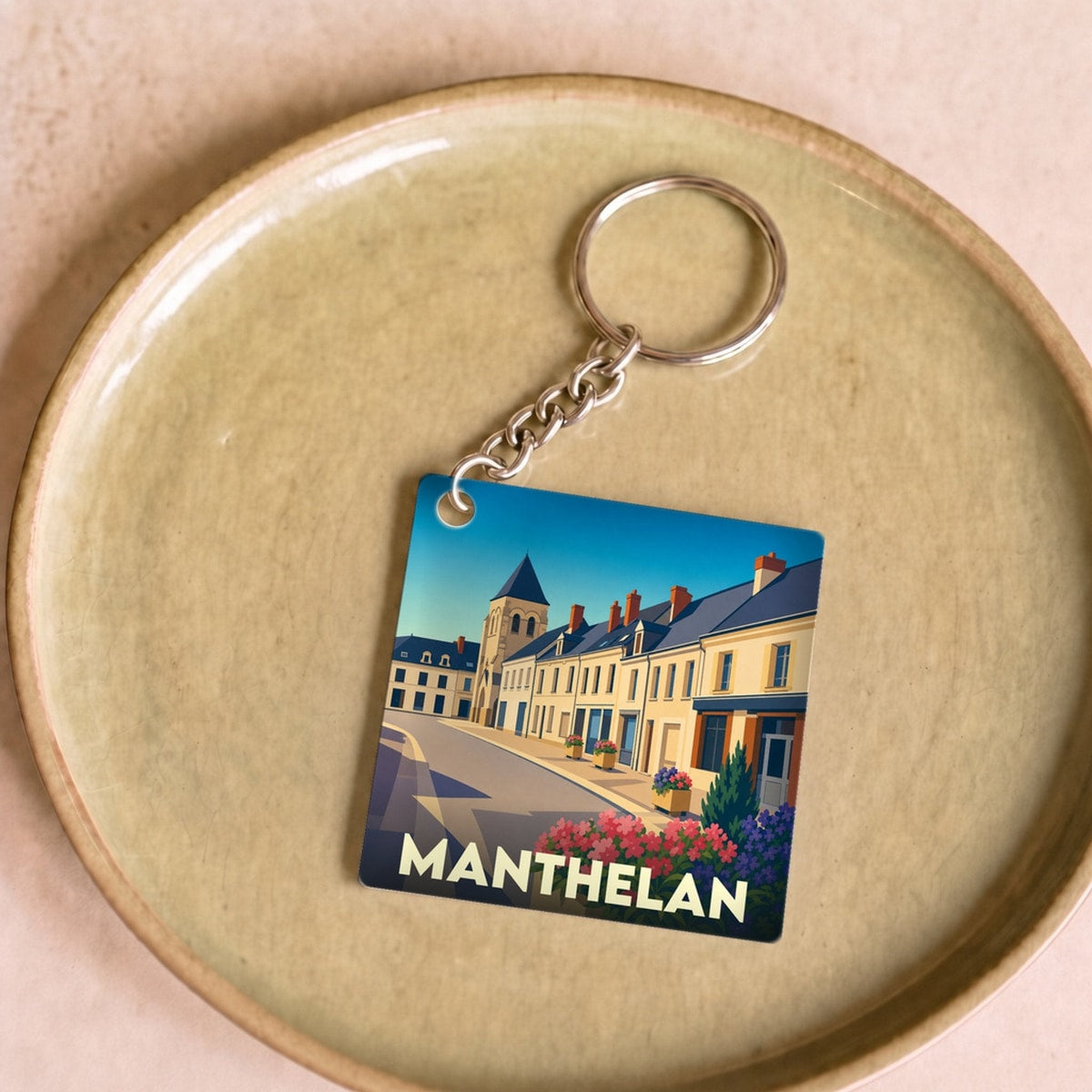 Porte-clés souvenir de la ville de Manthelan avec une illustration stylisée.