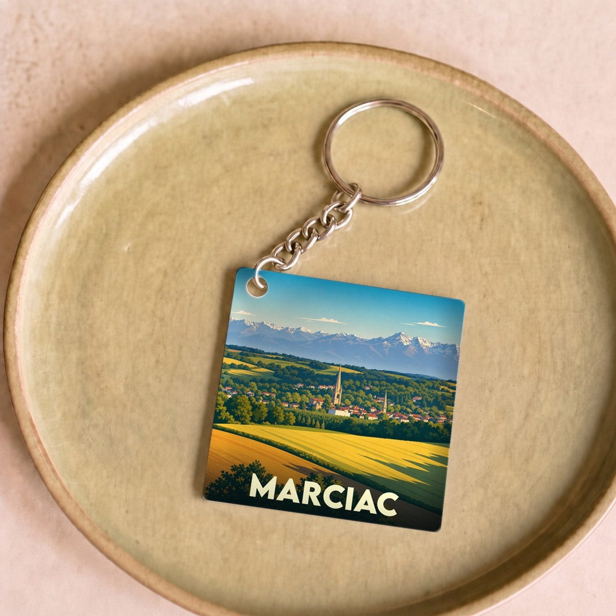 Porte-clés souvenir de la ville de Marciac avec une illustration stylisée de son paysage et de ses montagnes.