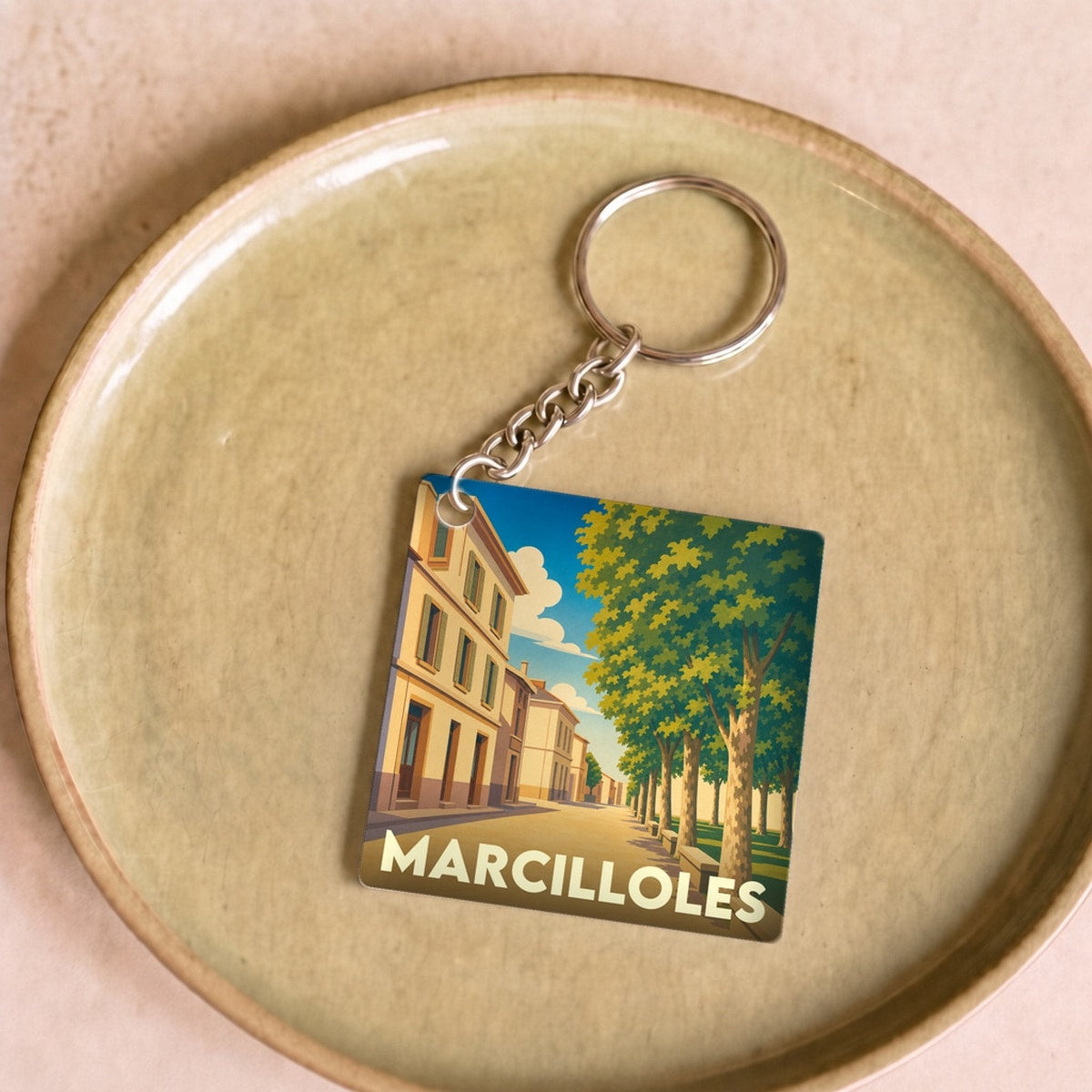Porte-clés souvenir de la ville de Marcilloles avec une illustration stylisée.