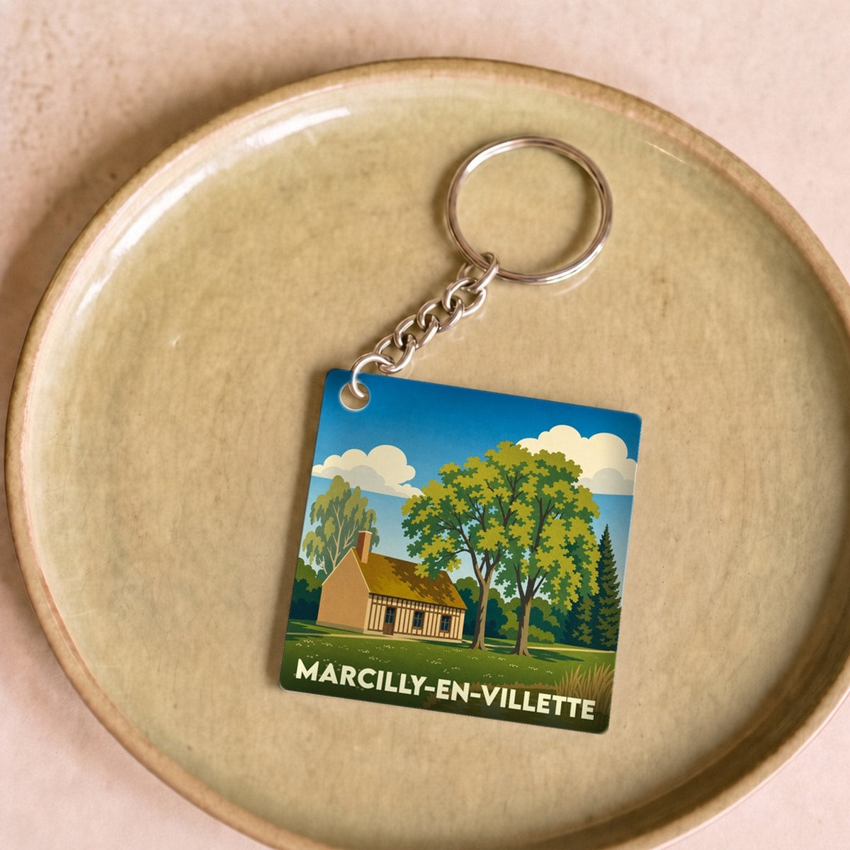 Porte-clés souvenir de la ville de Marcilly-en-Villette avec une illustration champêtre stylisée.
