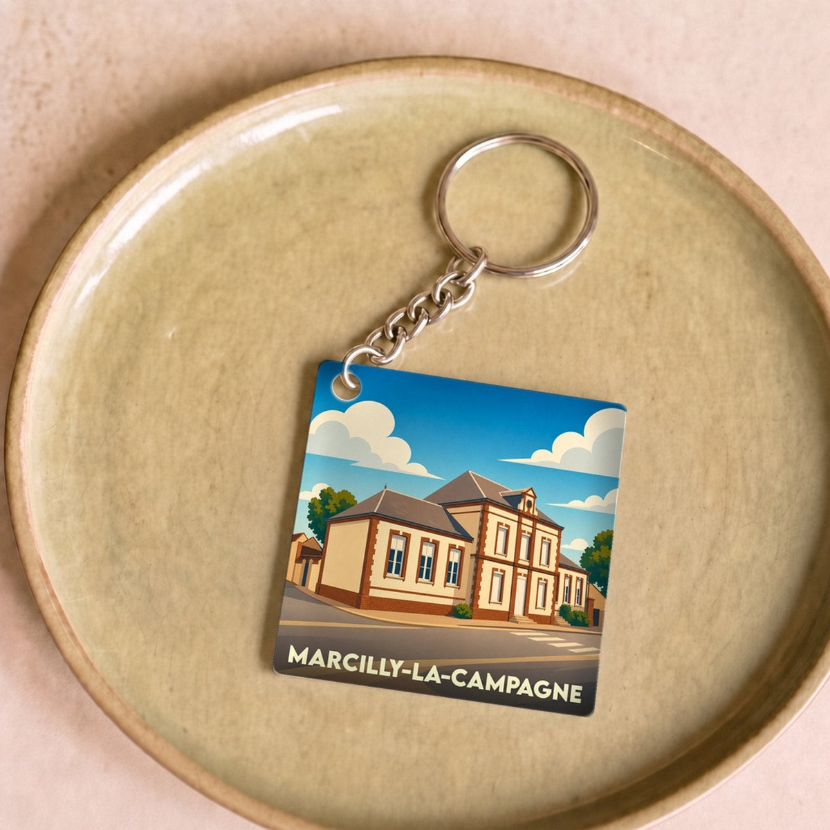 Porte-clés souvenir de la ville de Marcilly-la-Campagne avec une illustration stylisée.