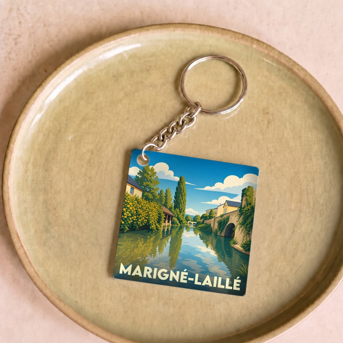 Porte-clés souvenir de la ville de Marigné-Laillé avec une illustration stylisée d'un paysage de rivière.