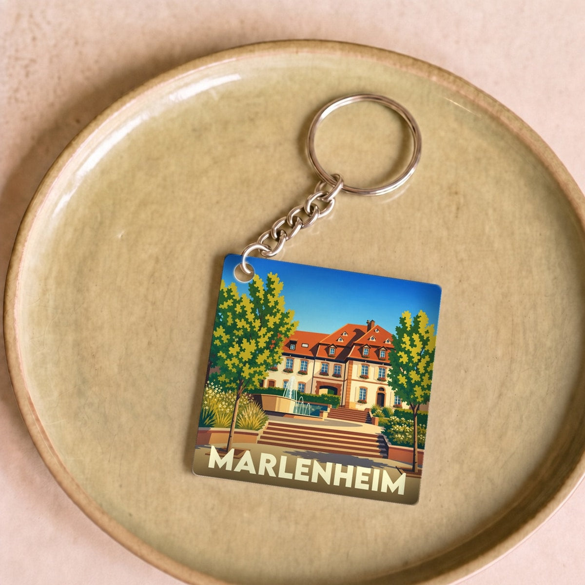 Porte-clés souvenir de la ville de Marlenheim avec une illustration stylisée d'une demeure traditionnelle alsacienne.