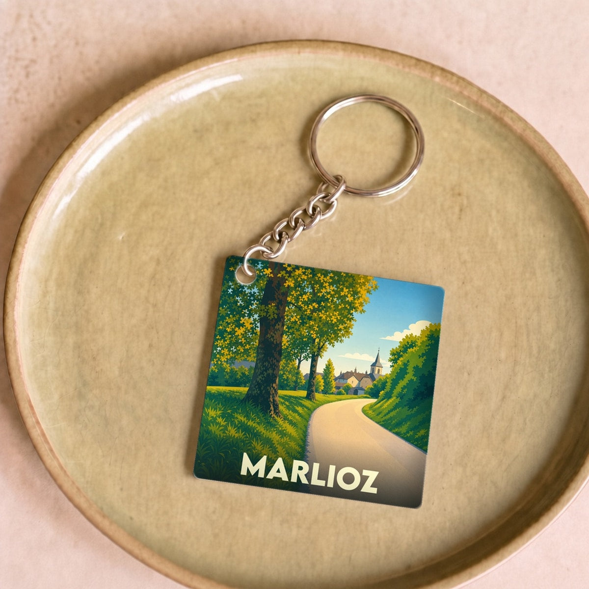 Porte-clés souvenir de la ville de Marlioz avec une illustration stylisée de paysage.