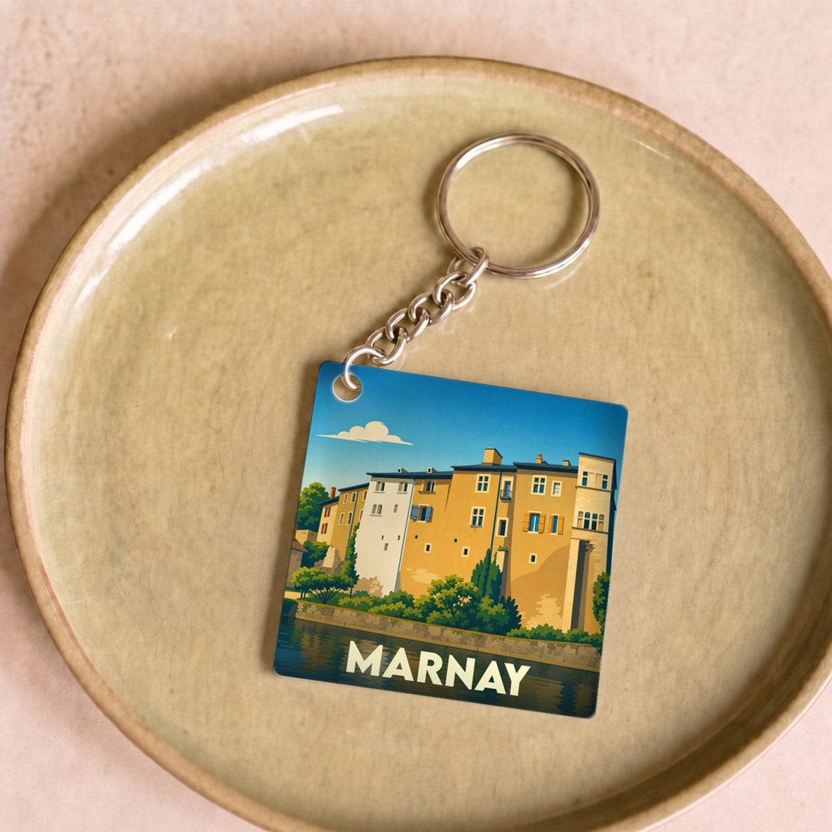 Porte-clés souvenir de la ville de Marnay avec une illustration stylisée d'un bâtiment au bord de l'eau.