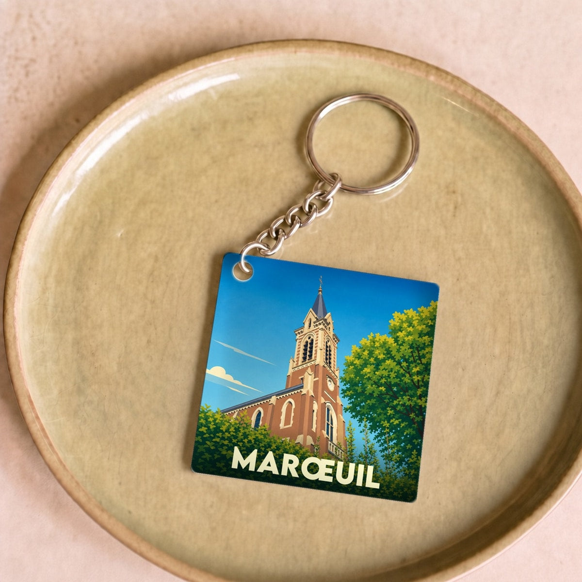 Porte-clés souvenir de la ville de Marœuil avec une illustration stylisée de son église.
