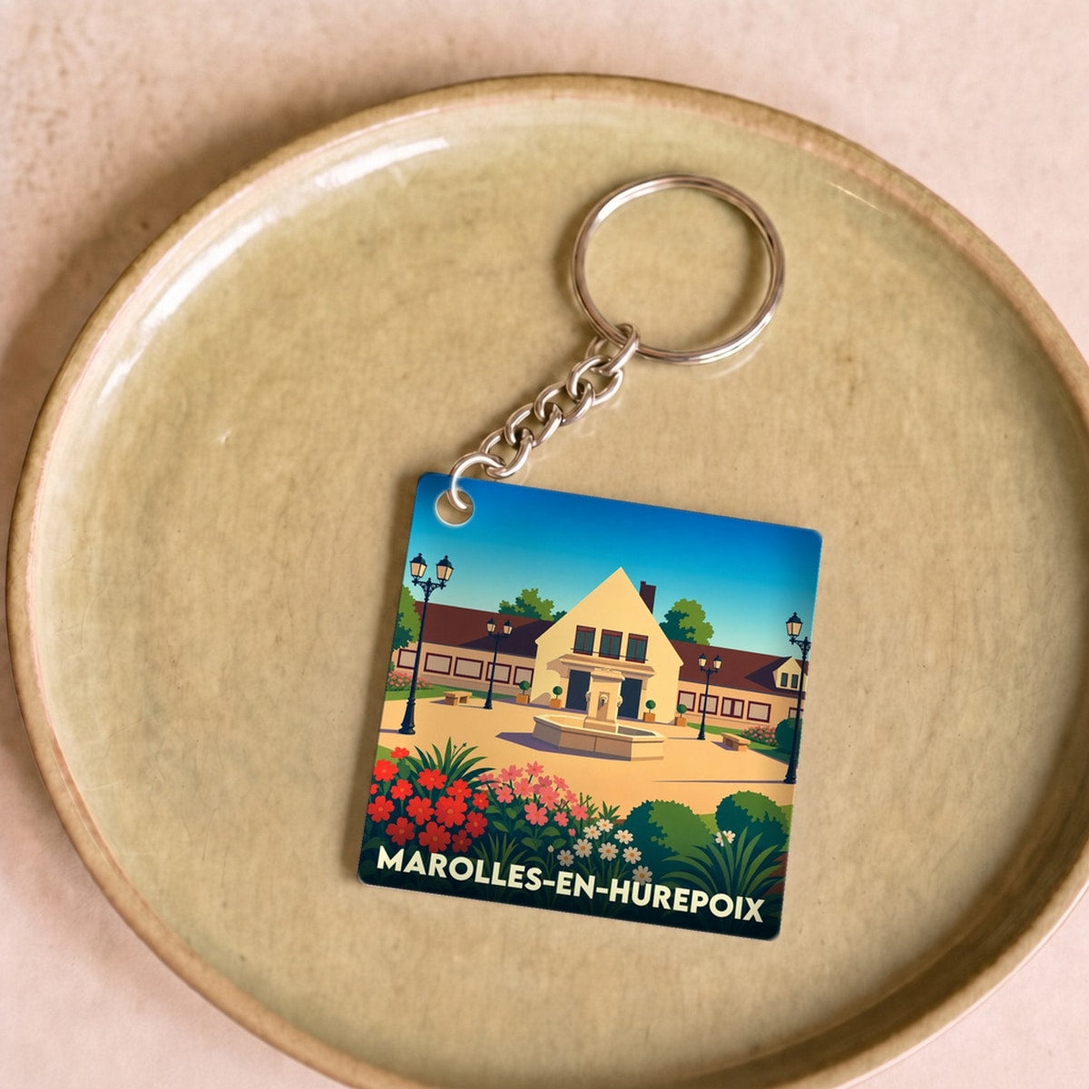 Porte-clés souvenir de la ville de Marolles-en-Hurepoix avec une illustration stylisée.