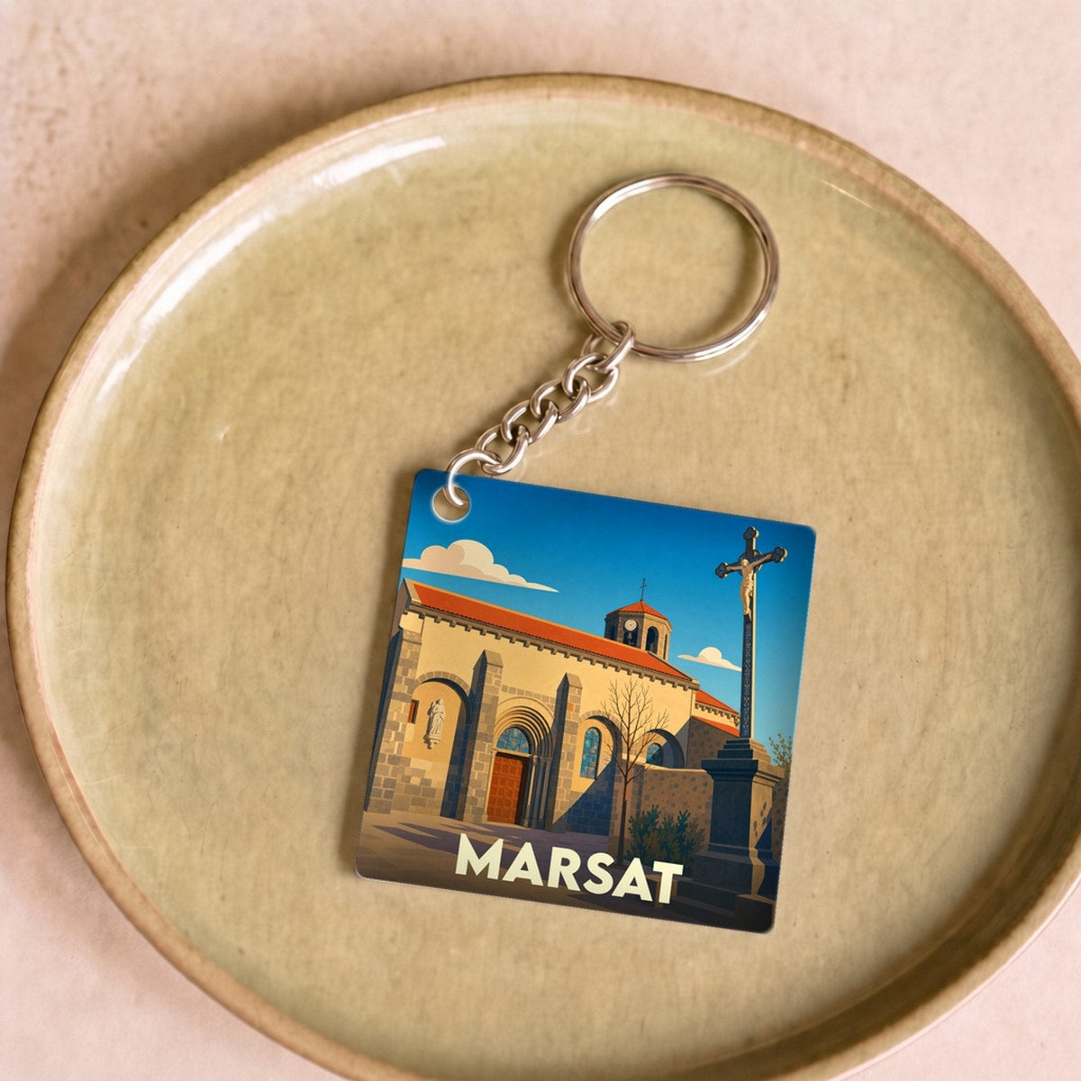 Porte-clés souvenir de la ville de Marsat avec une illustration stylisée de son église.