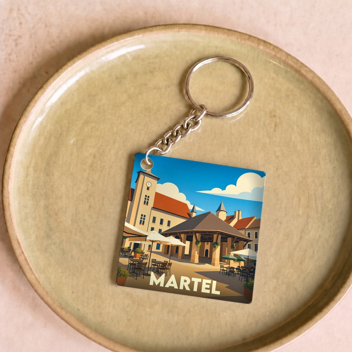 Porte-clés souvenir de la ville de Martel avec une illustration stylisée de sa place principale.