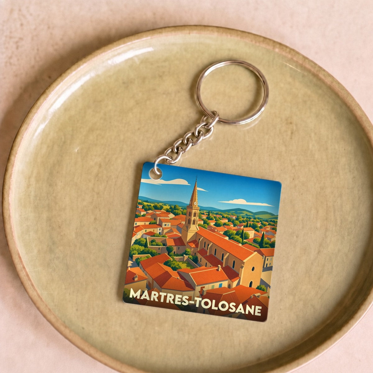 Porte-clés souvenir de la ville de Martres-Tolosane avec une illustration stylisée de ses toits et de son clocher.