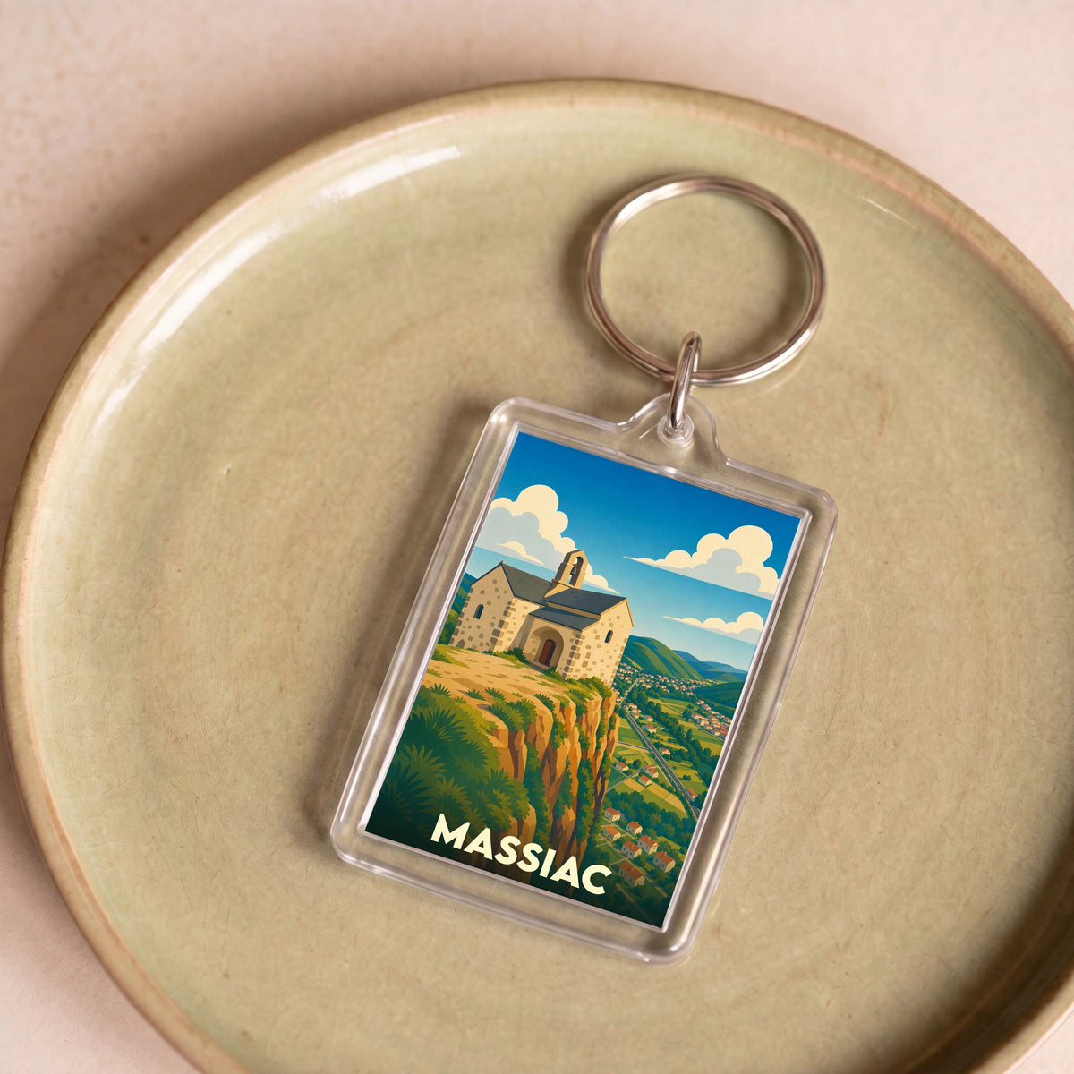 Porte-clés souvenir de la ville de Massiac avec une illustration stylisée d'une chapelle sur une falaise.