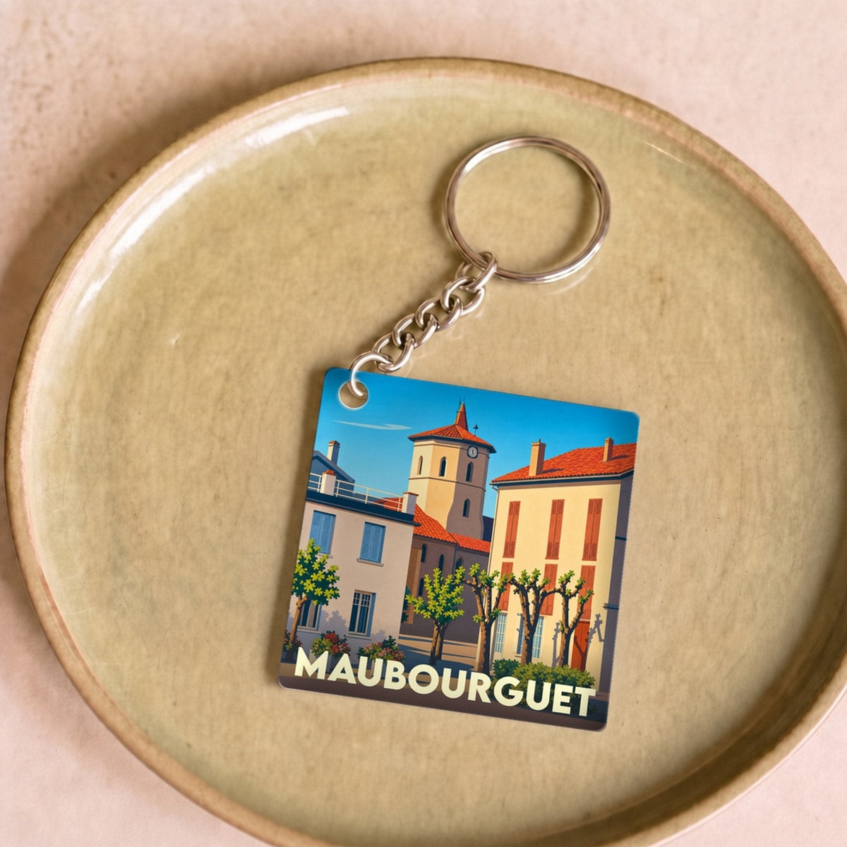 Porte-clés souvenir de la ville de Maubourguet avec une illustration stylisée.