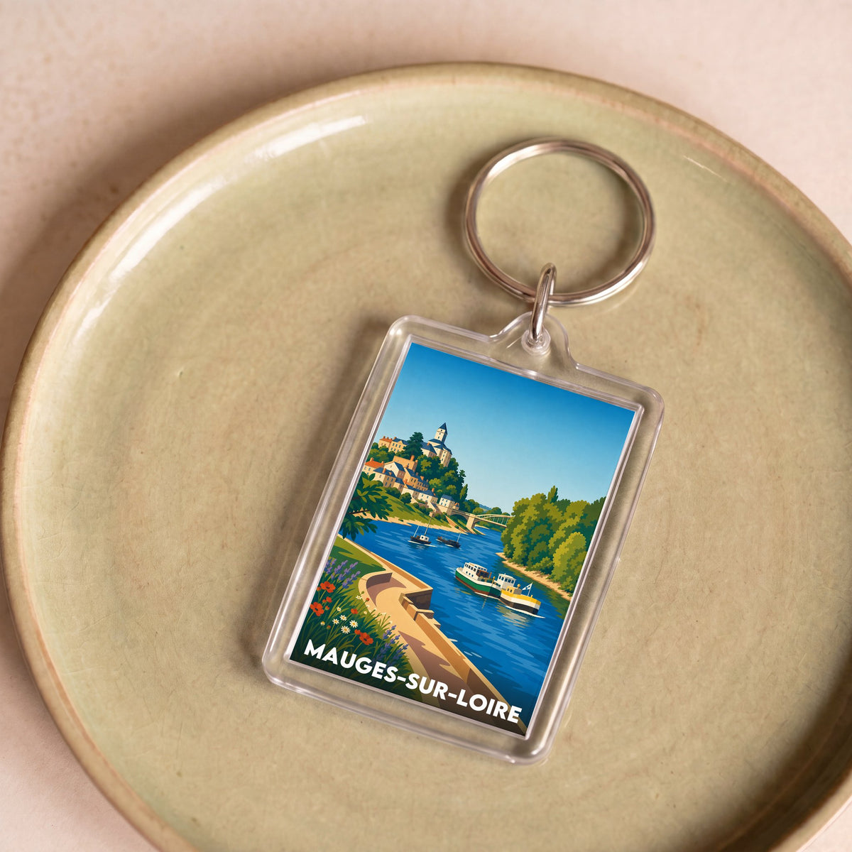 Porte-clés souvenir de la ville de Mauges-sur-Loire avec une illustration stylisée d'un paysage fluvial.