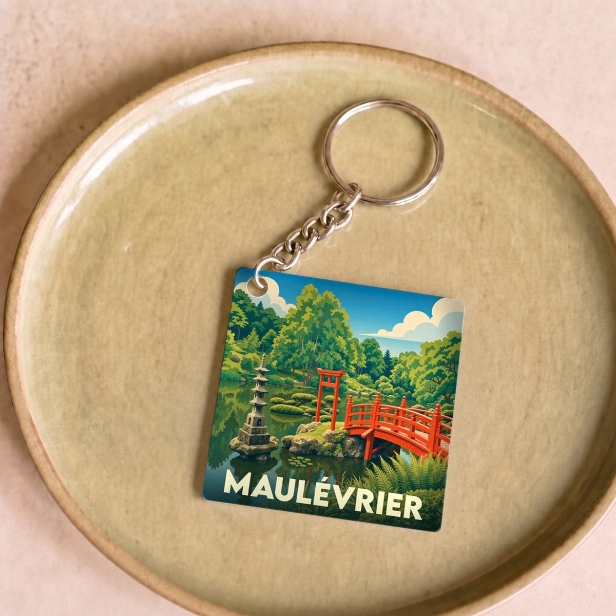 Porte-clés souvenir de la ville de Maulévrier illustrant son jardin japonais avec un pont rouge et une pagode.