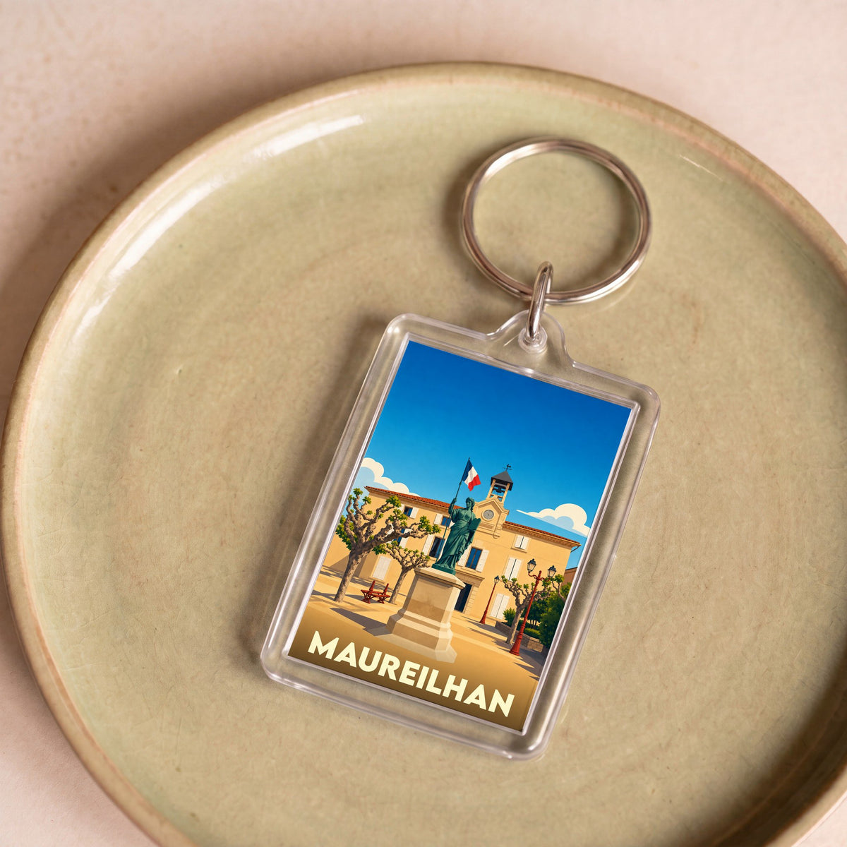 Porte-clés souvenir de la ville de Maureilhan avec une illustration stylisée.