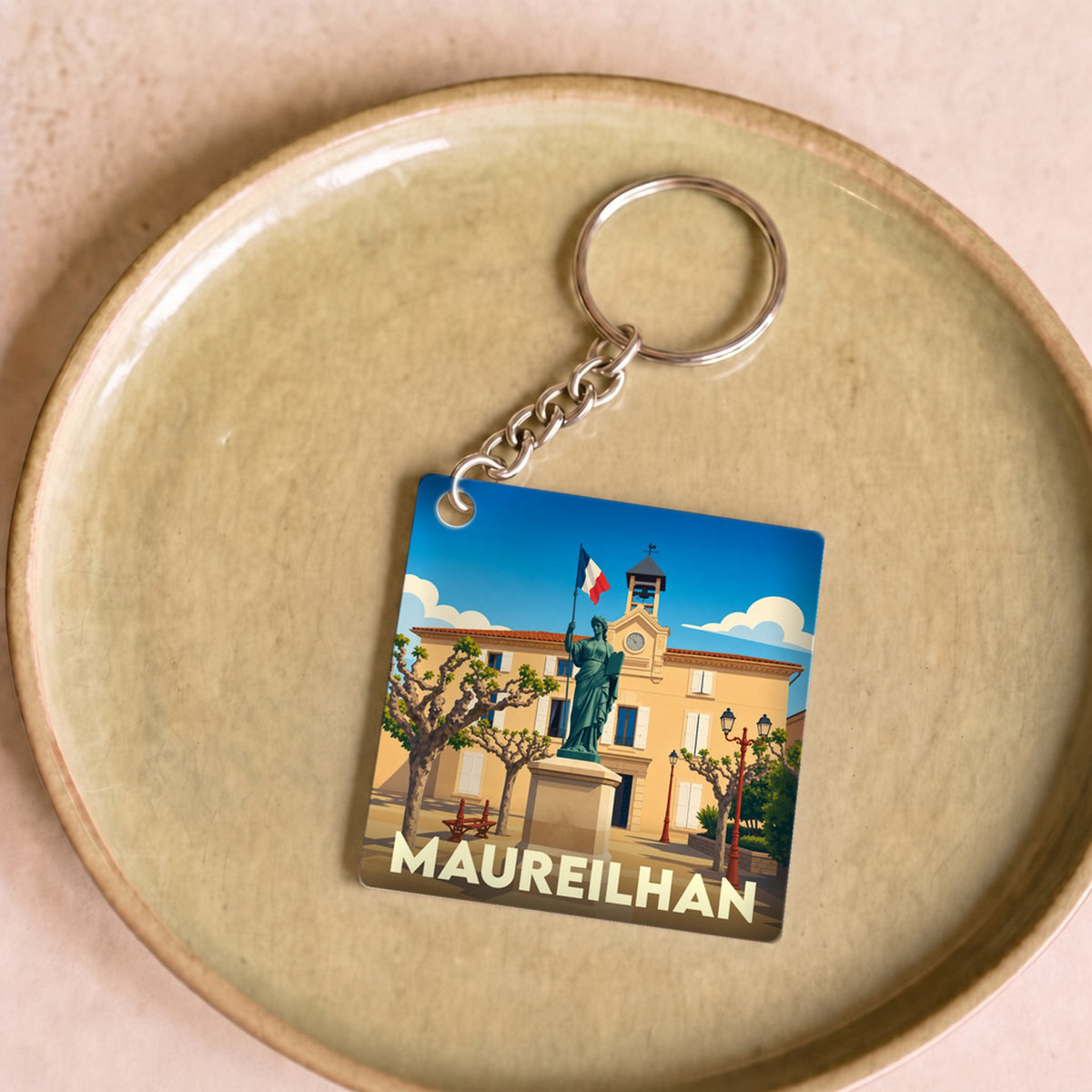Porte-clés souvenir de la ville de Maureilhan avec une illustration stylisée.