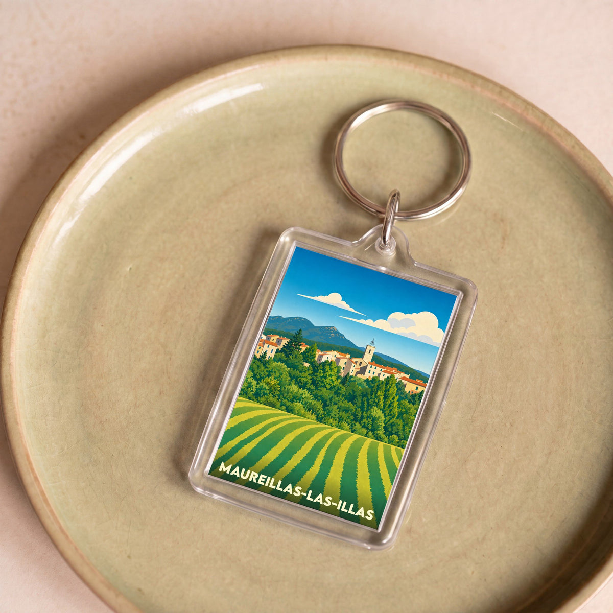 Porte-clés souvenir de la ville de Maureillas-las-Illas avec une illustration stylisée de son paysage.