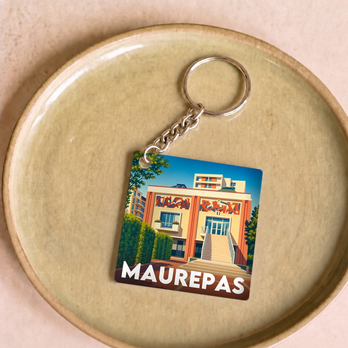 Porte-clés souvenir de la ville de Maurepas avec une illustration stylisée.