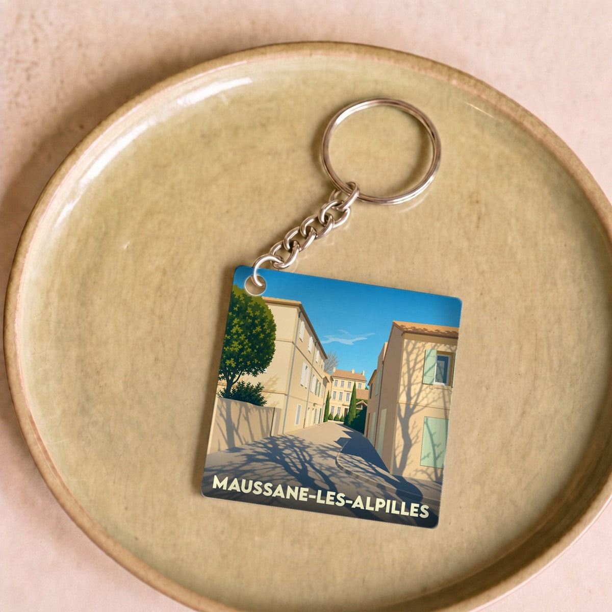 Porte-clés souvenir de la ville de Maussane-les-Alpilles avec une illustration stylisée.