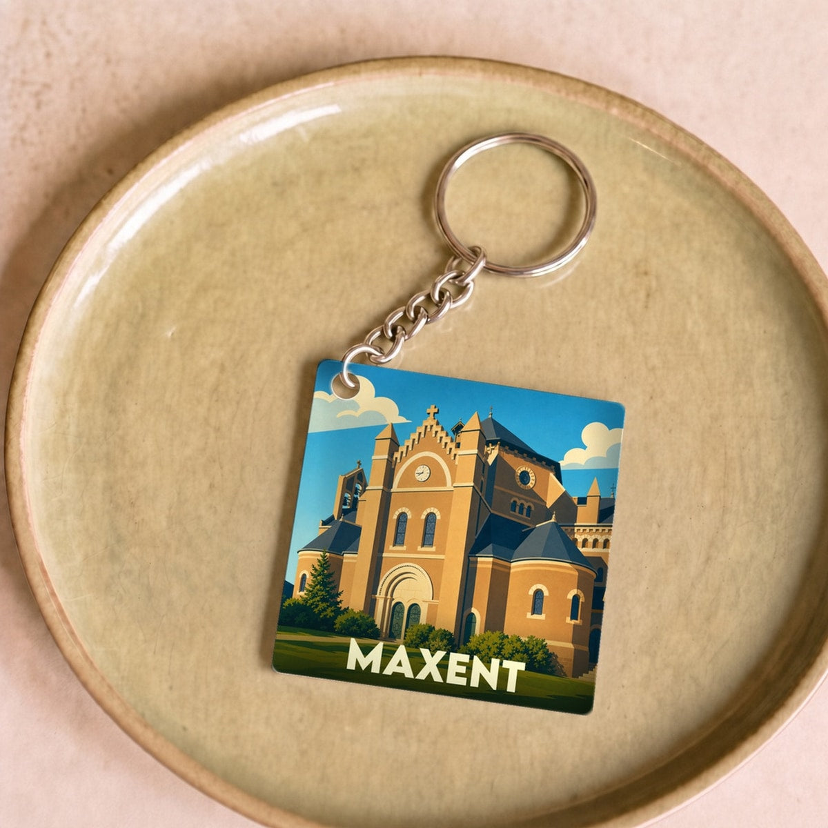 Porte-clés souvenir de la ville de Maxent avec une illustration stylisée de son église.