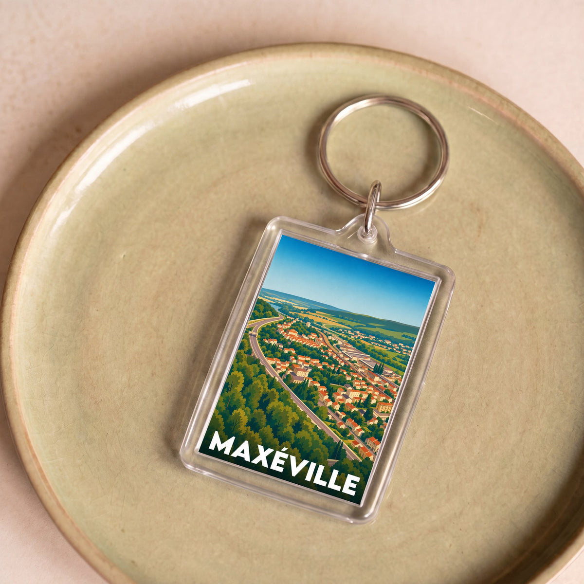 Porte-clés souvenir de la ville de Maxéville avec une illustration aérienne stylisée.